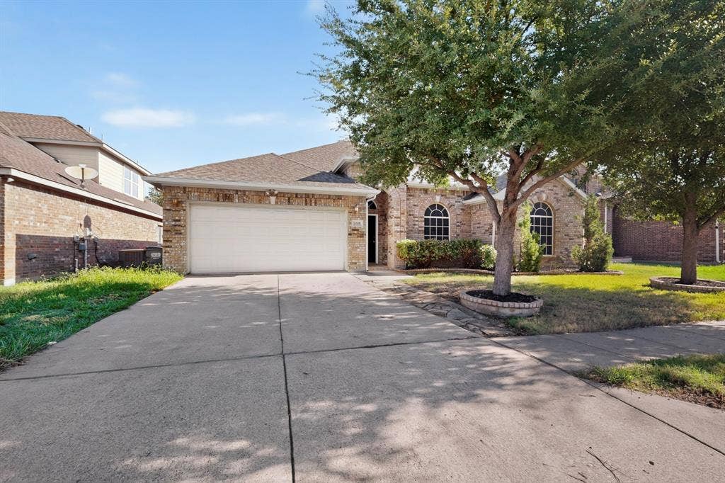 14908 Riverside Drive, Little Elm, TX 75068 Brick exterior with arched windows, an attached two-car garage, and a concrete driveway