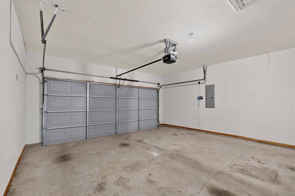 14908 Riverside Drive, Little Elm, TX 75068 Attached garage with a gray sectional door, concrete flooring, and an overhead door opener