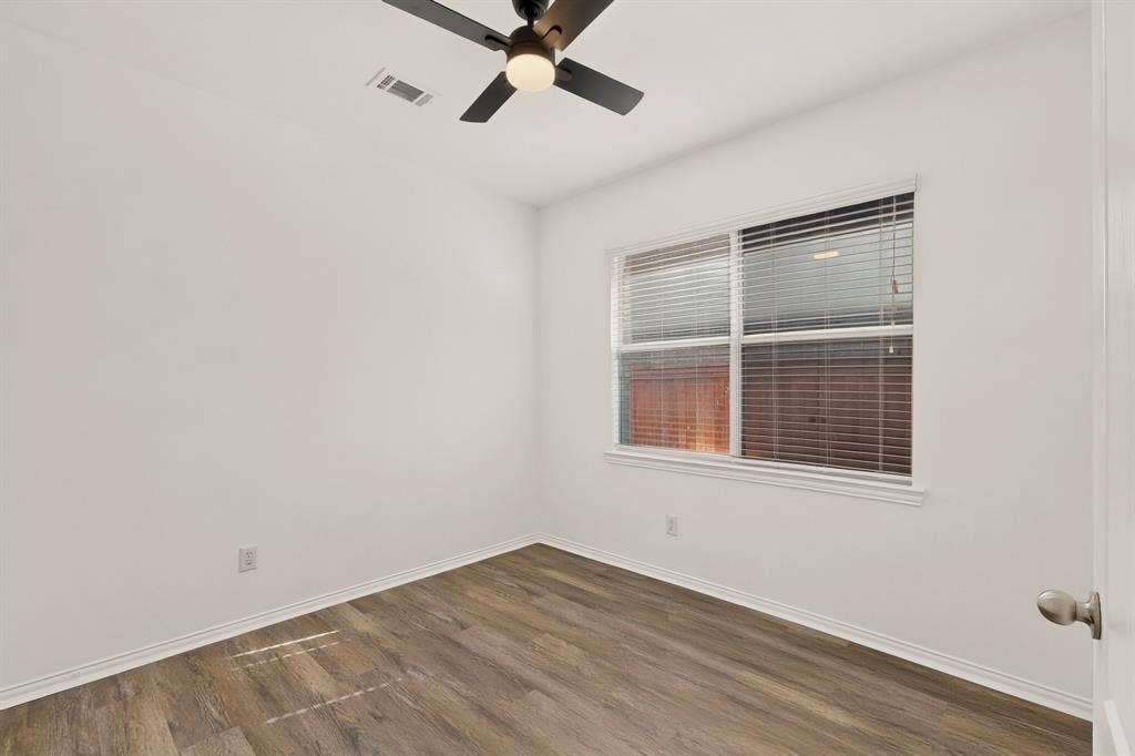 14908 Riverside Drive, Little Elm, TX 75068 Wood-finish flooring, white walls, double window with blinds, ceiling fan with integrated lighting, and a white door with a satin nickel knob