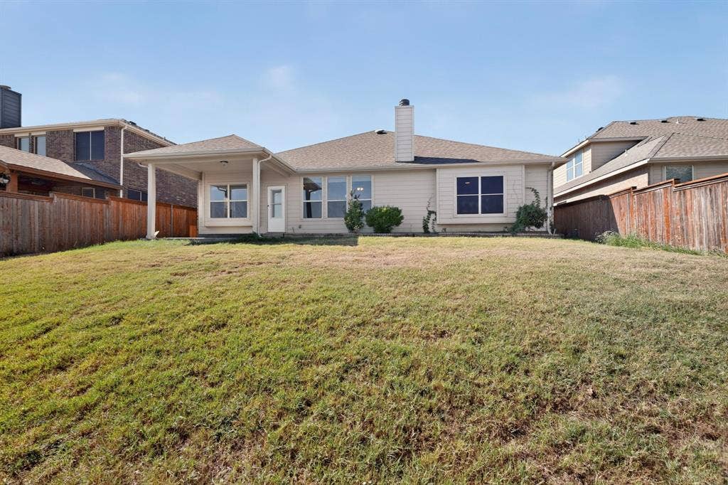 14908 Riverside Drive, Little Elm, TX 75068 Charming single-story residence featuring a spacious rear lawn, professional landscaping with mature foundation plantings, and a clean architectural design with multiple windows allowing natural light throughout
