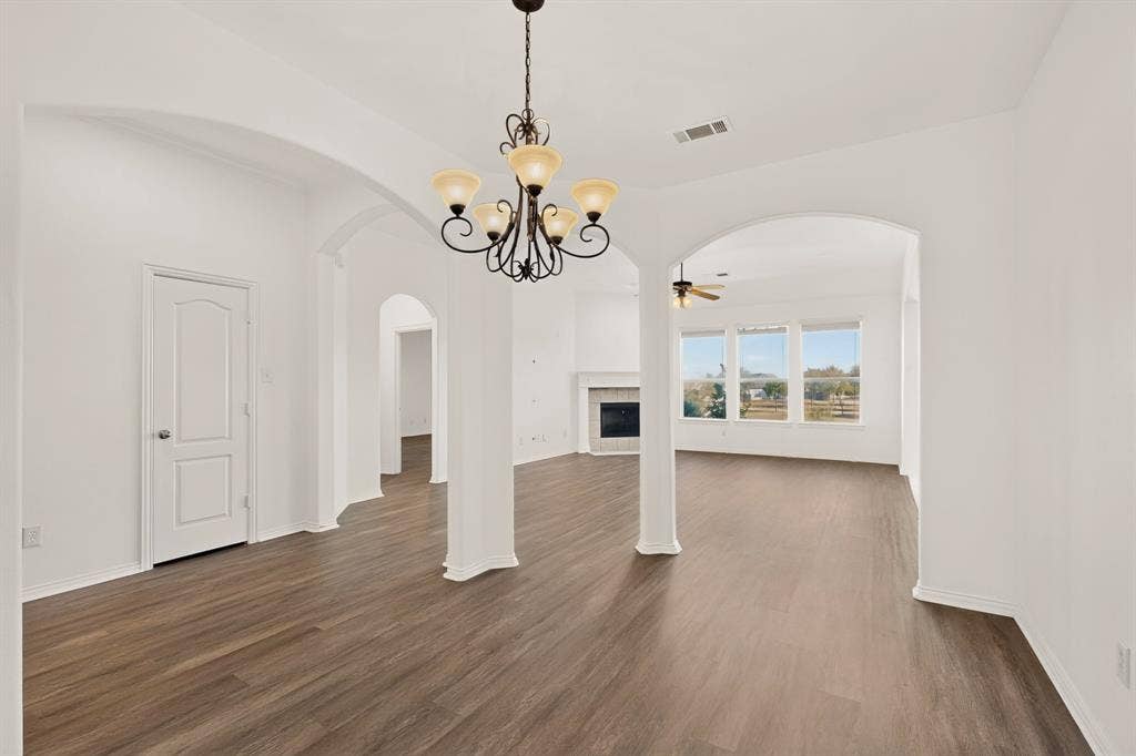 14908 Riverside Drive, Little Elm, TX 75068 Open-concept living area featuring wood-finish flooring, arched doorways, a chandelier, and ample natural light from multiple windows