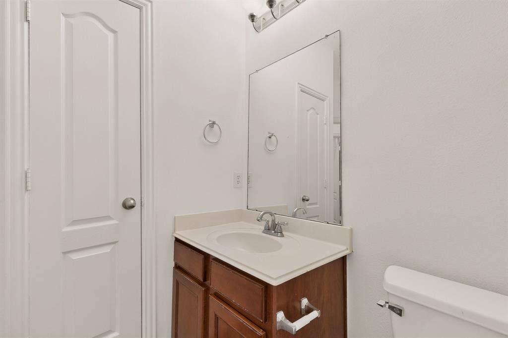 14908 Riverside Drive, Little Elm, TX 75068 Bathroom vanity with integrated sink, wood-finish cabinetry, and a large wall-mounted mirror