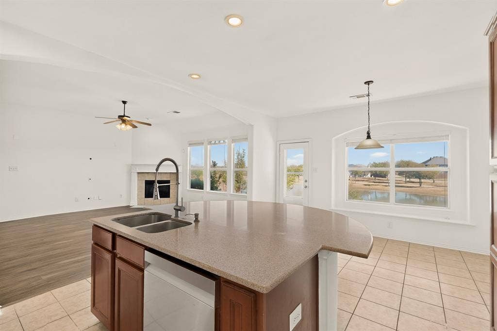 14908 Riverside Drive, Little Elm, TX 75068 Spacious kitchen island with a double basin sink, solid surface countertop, and wood cabinetry