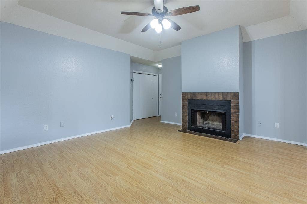 2308 Melissa Drive, #H5, Waco, TX 76708 Wood-finish flooring, brick-surround fireplace, ceiling fan with integrated lighting, and bi-fold closet doors