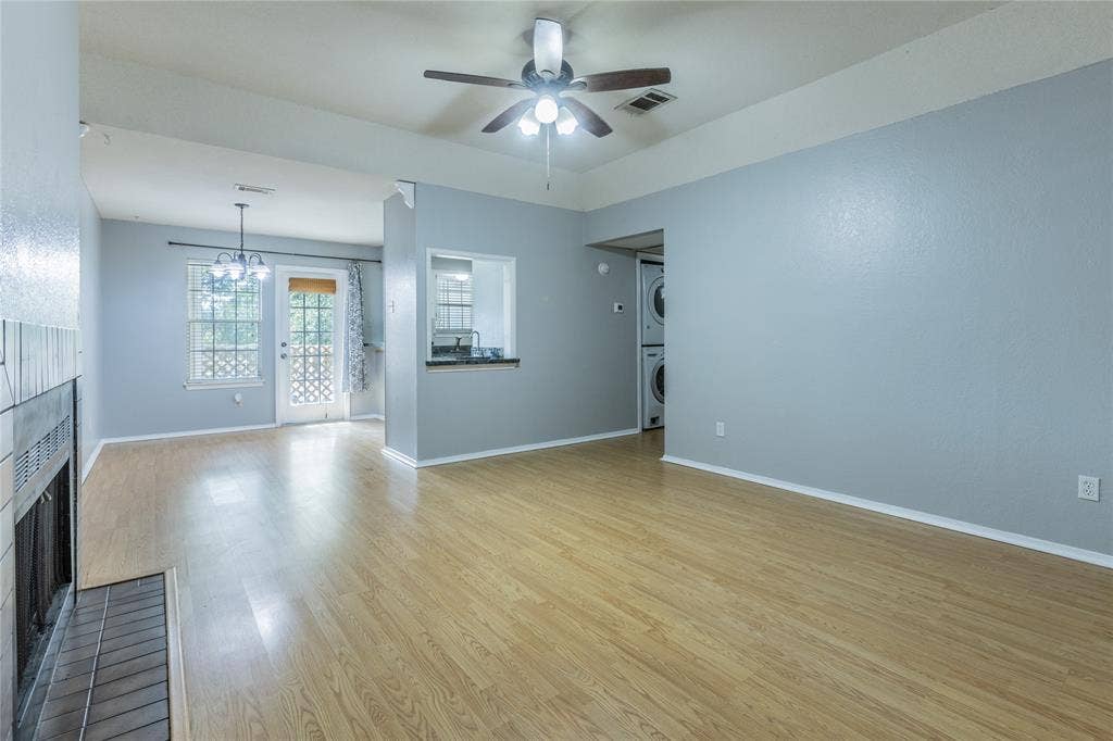 2308 Melissa Drive, #H5, Waco, TX 76708 Vaulted ceiling, wood-finish flooring, fireplace with tile surround, built-in pass-through window, and stacked laundry appliances