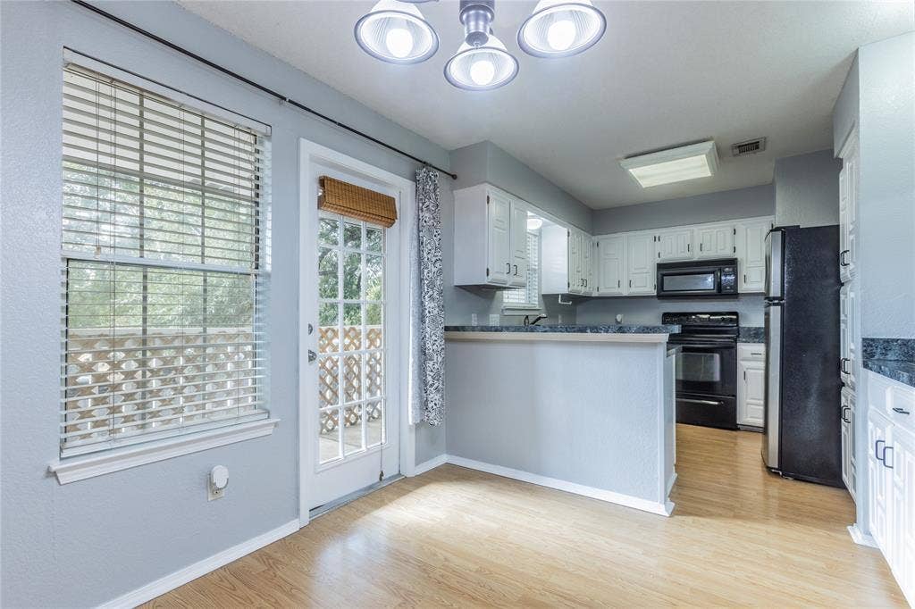2308 Melissa Drive, #H5, Waco, TX 76708 Kitchen with white cabinetry, black appliances, dark countertops, and wood-finish flooring