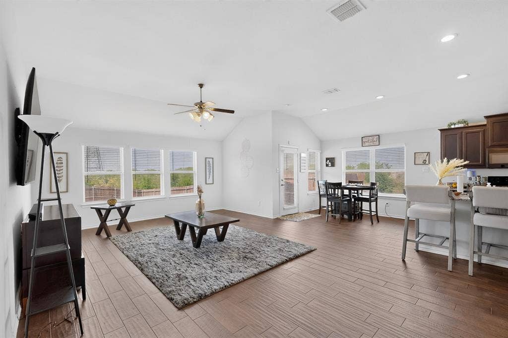 11700 Aldermoor Court, Fort Worth, TX 76036 Vaulted ceilings with a ceiling fan, wood-finish flooring, a kitchen island with seating, a dining area, and multiple windows