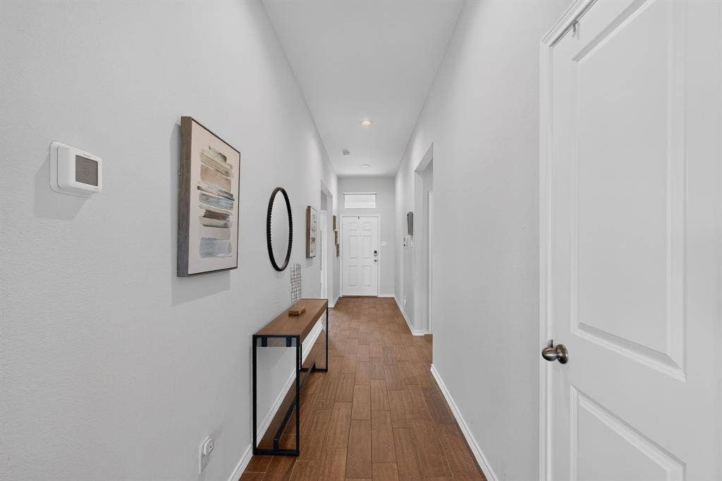 11700 Aldermoor Court, Fort Worth, TX 76036 Wood-finish flooring throughout a neutral-toned hallway with recessed lighting and white paneled doors