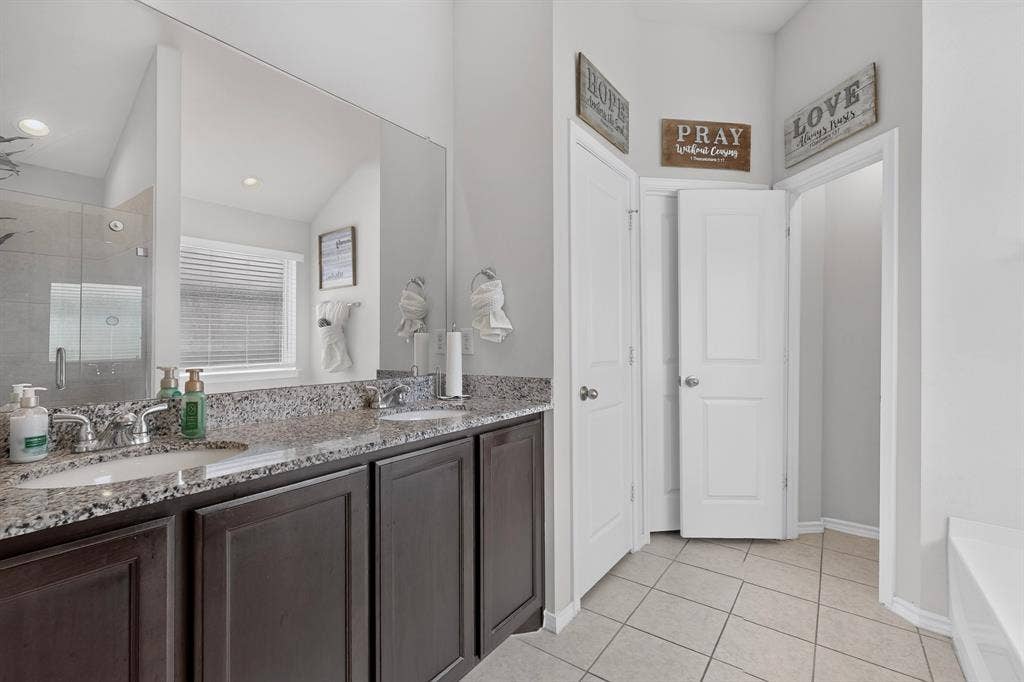 11700 Aldermoor Court, Fort Worth, TX 76036 Double vanity with granite-style countertop, dual undermount sinks, chrome fixtures, and dark wood-finish cabinetry