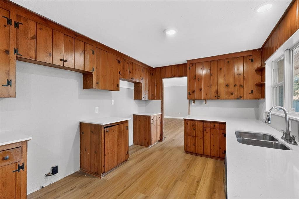 2314 Wales Place, Irving, TX 75062 Kitchen featuring extensive wood cabinetry, wood-finish flooring, recessed lighting, white countertops, and a double basin stainless steel sink with a pull-down faucet