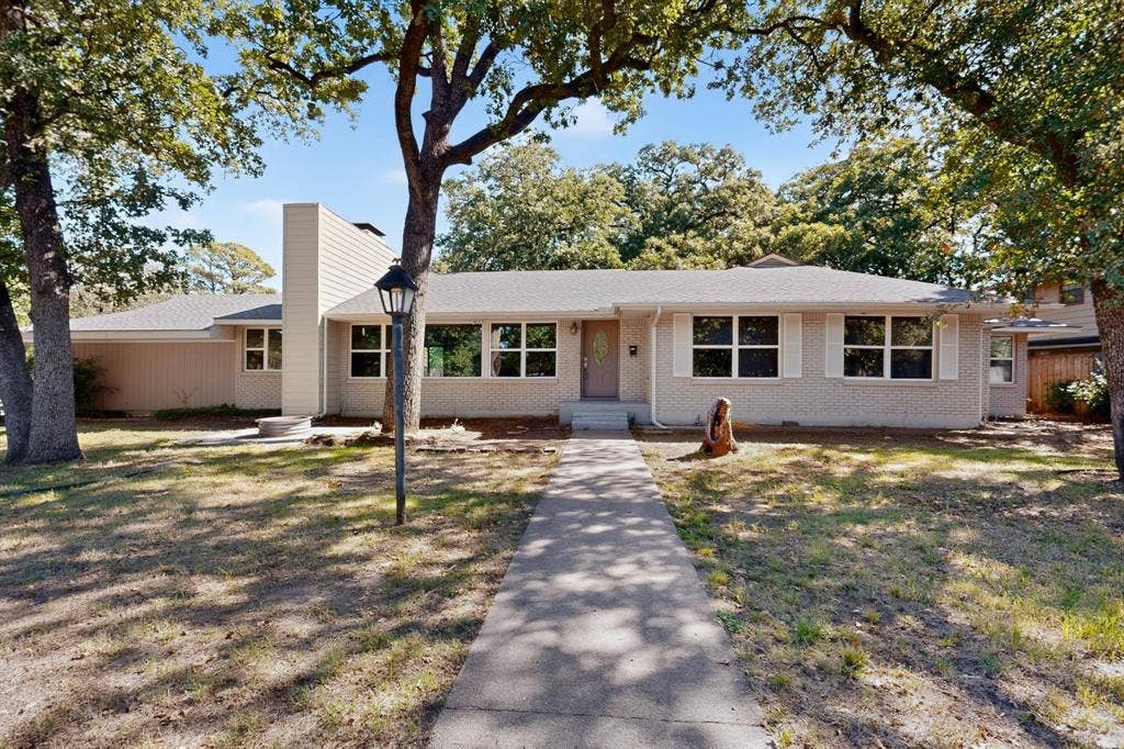 2314 Wales Place, Irving, TX 75062 Single-story dwelling with a light-colored brick facade, multiple window banks, and a prominent chimney feature