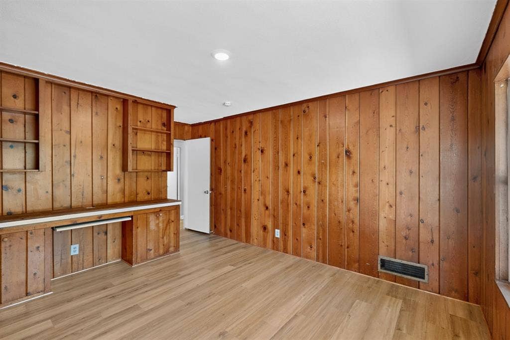 2314 Wales Place, Irving, TX 75062 Wood-paneled walls featuring built-in shelving, integrated desk, and wood-finish flooring