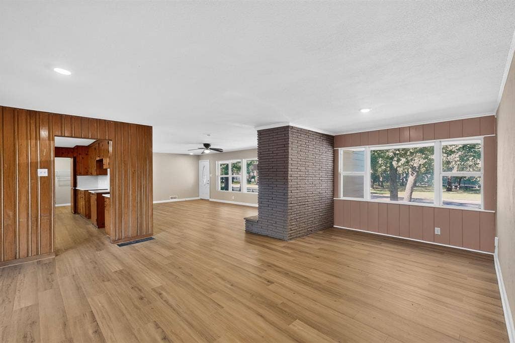2314 Wales Place, Irving, TX 75062 Open-concept living space with wood-finish flooring, a brick accent wall, and multiple windows