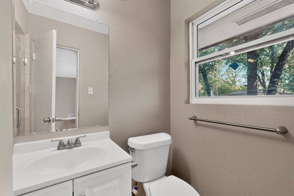2314 Wales Place, Irving, TX 75062 White vanity with integrated sink, brushed nickel faucet, wall-mounted mirror, and a window with natural light