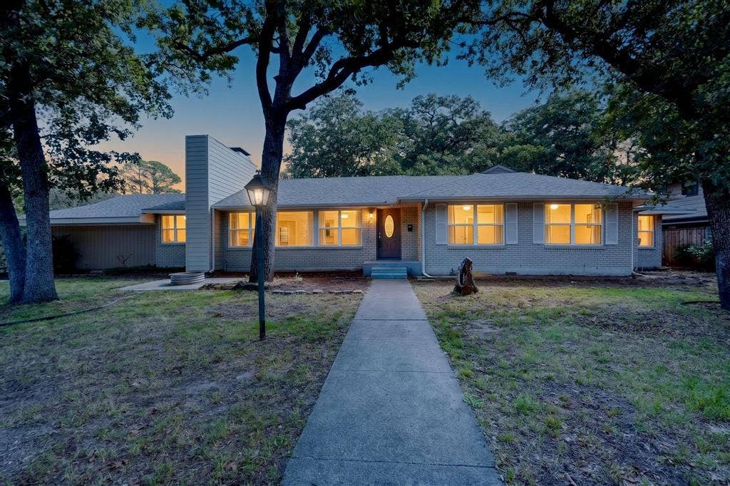 2314 Wales Place, Irving, TX 75062 Brick veneer exterior with a concrete walkway, mature trees, and a prominent chimney feature