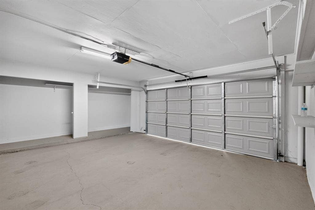 2314 Wales Place, Irving, TX 75062 Spacious garage with an automatic overhead door, concrete flooring, and built-in shelving