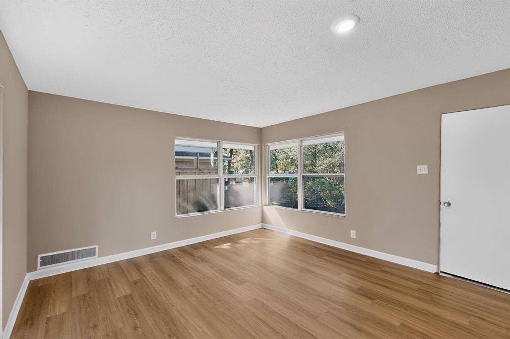 2314 Wales Place, Irving, TX 75062 Wood-finish flooring throughout, multiple windows, recessed ceiling lighting, neutral wall tones, and white trim