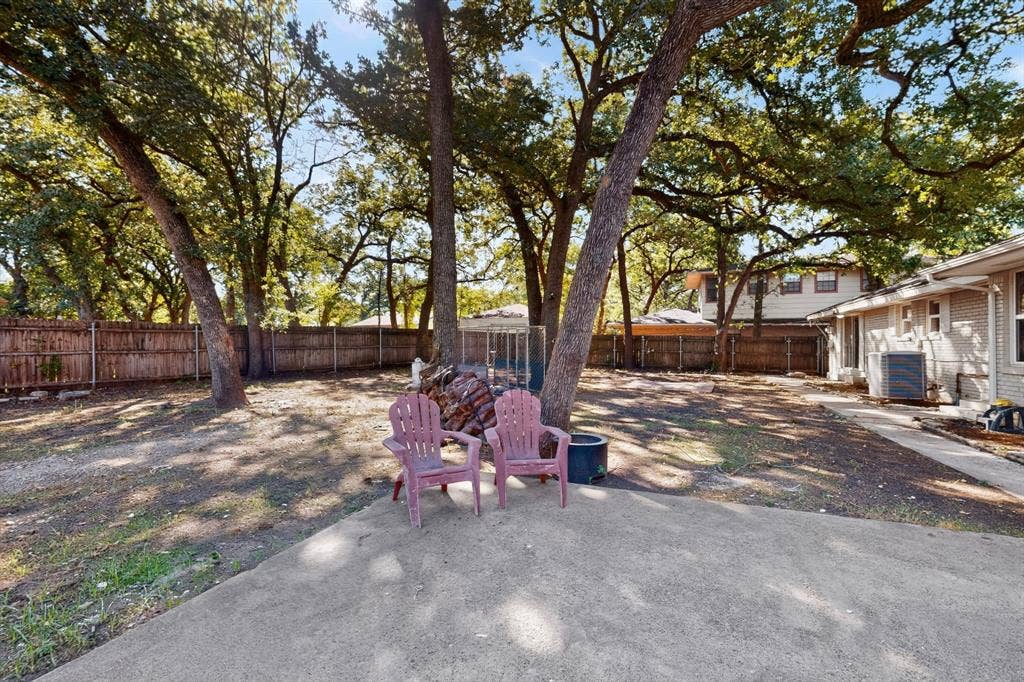2314 Wales Place, Irving, TX 75062 Expansive backyard featuring mature trees, a wood privacy fence, and a concrete patio
