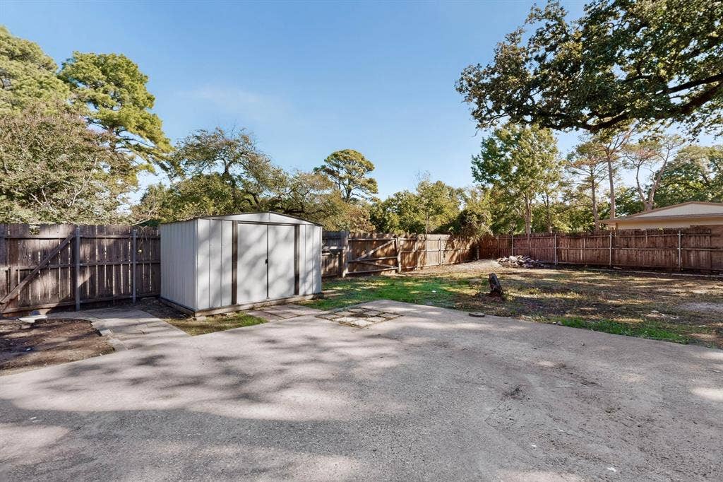 2314 Wales Place, Irving, TX 75062 Spacious backyard featuring mature landscaping, lush green lawn, and a detached storage structure with modern finishes