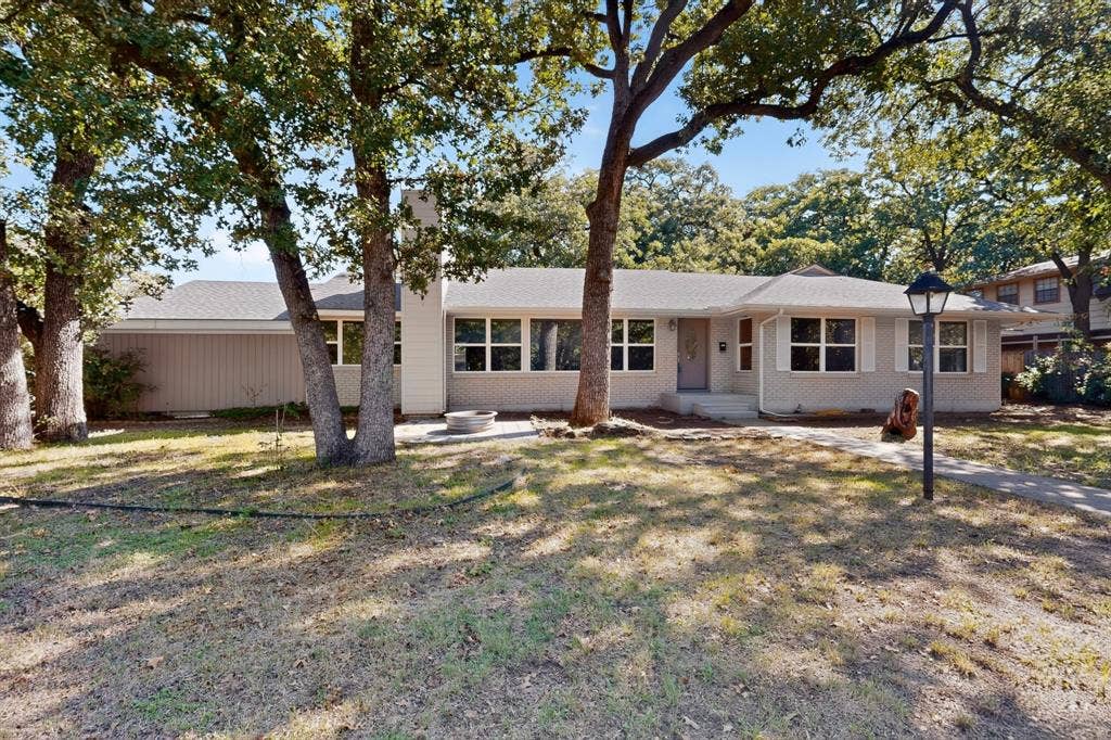 2314 Wales Place, Irving, TX 75062 Ranch-style exterior with a light-colored brick facade, multiple windows, a prominent front door, and a concrete walkway