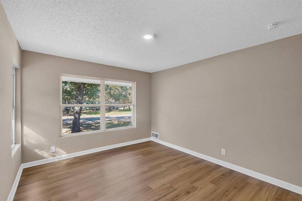 2314 Wales Place, Irving, TX 75062 Wood-finish flooring, neutral wall tones, white trim, and a large multi-pane window
