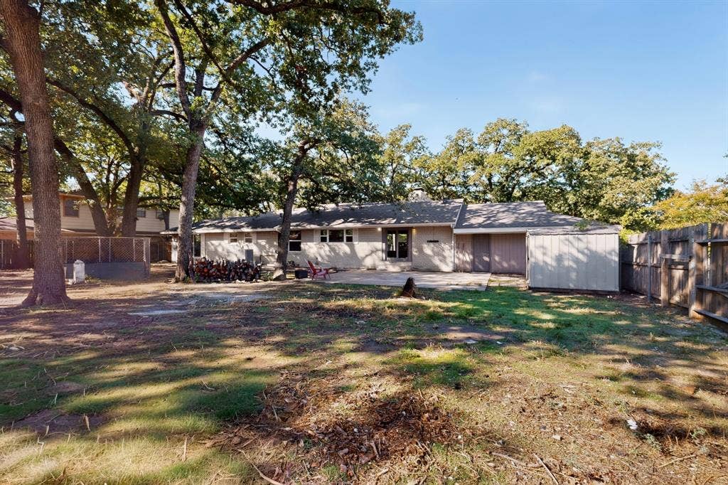 2314 Wales Place, Irving, TX 75062 Expansive rear yard with mature trees, a concrete patio, and a utility shed