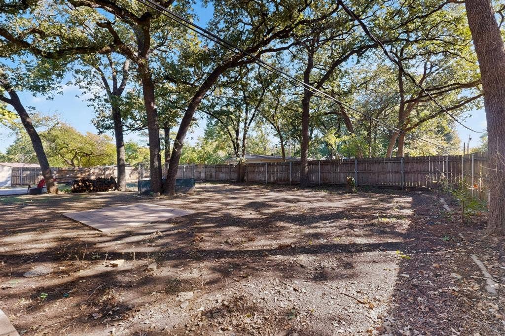 2314 Wales Place, Irving, TX 75062 Expansive fenced yard featuring mature trees and a concrete patio
