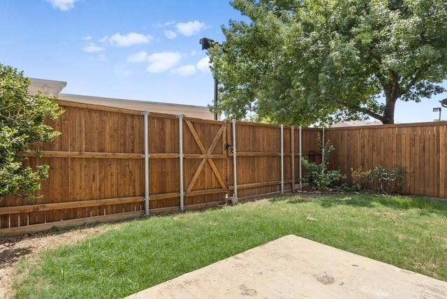 7944 Eddie Drive, Plano, TX 75025 Private backyard featuring a full wood fence with gate, concrete patio, and mature landscaping