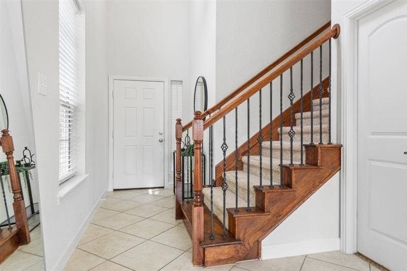 7944 Eddie Drive, Plano, TX 75025 Wood staircase with decorative wrought iron spindles and carpeted treads