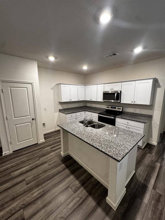 1813 Chapel Hill Road, Princeton, TX 75407 Modern kitchen featuring an island with a stainless steel sink, granite-style countertops, white cabinetry, and wood-finish flooring