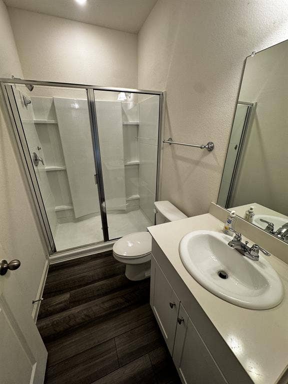 1813 Chapel Hill Road, Princeton, TX 75407 Walk-in shower with glass enclosure, single vanity with integrated sink, wood-finish flooring, and wall-mounted mirror