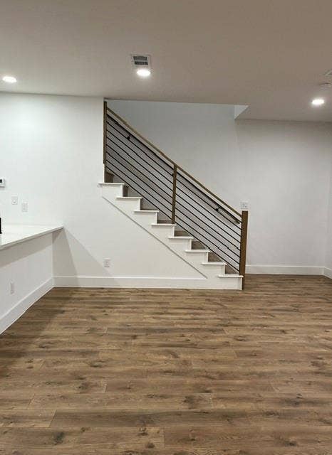 9473 Timberleaf Drive, Dallas, TX 75243 Wood-finish flooring, staircase with metal and wood railing, recessed ceiling lighting, and white baseboards