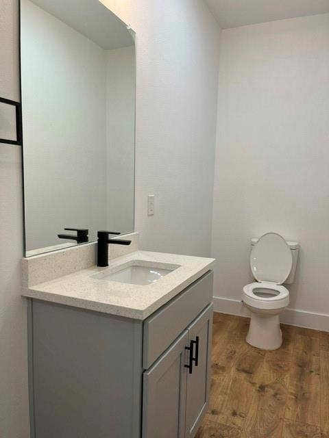 9473 Timberleaf Drive, Dallas, TX 75243 Gray vanity with matte black hardware, white countertop, integrated sink, matte black faucet, and wood-finish flooring