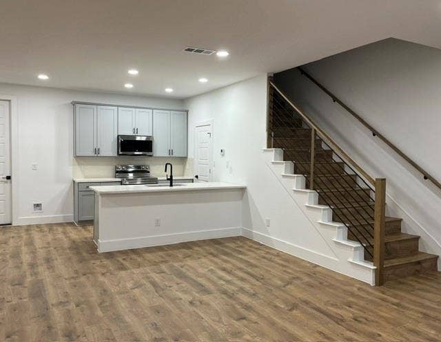 9473 Timberleaf Drive, Dallas, TX 75243 Open-concept living area with wood-finish flooring, recessed lighting, and a contemporary staircase featuring wood treads and a cable railing system