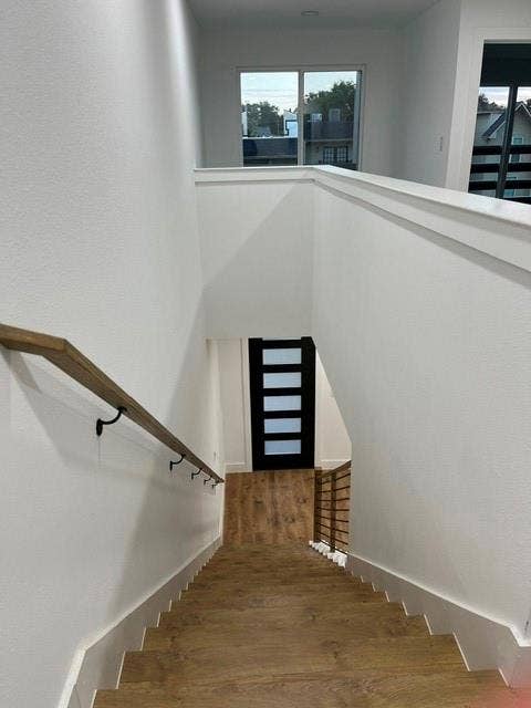 9473 Timberleaf Drive, Dallas, TX 75243 Wood-finish flooring on stairs and landing, modern full-light panel door, and multiple windows