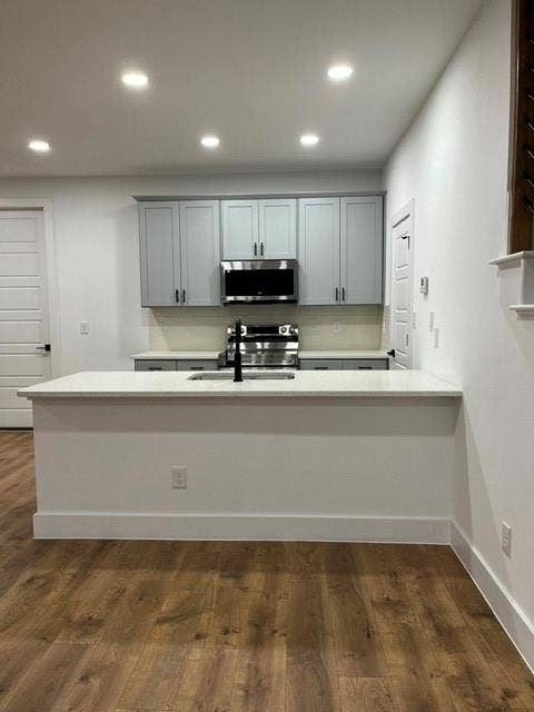 9473 Timberleaf Drive, Dallas, TX 75243 Kitchen featuring a stone-finish countertop, wood-finish flooring, recessed lighting, stainless steel appliances, and gray cabinetry