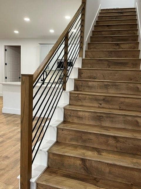 9473 Timberleaf Drive, Dallas, TX 75243 Staircase with wood-finish treads and risers, black metal balusters, and a natural wood handrail