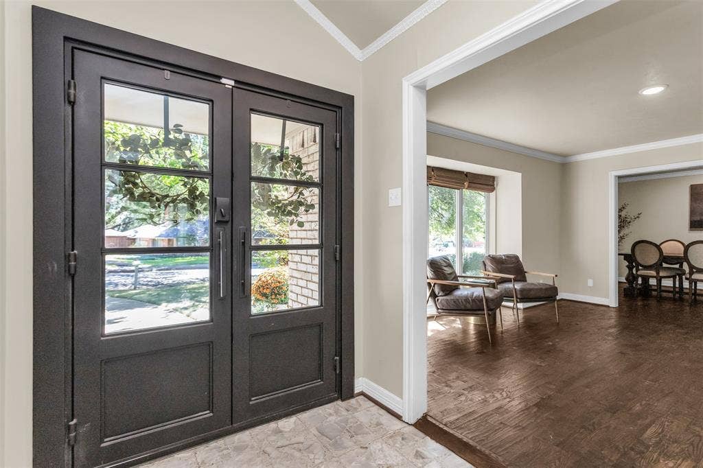 Double-entry doors with glass panes, crown molding, and recessed ceiling light,  The hand-scraped floors continue through most of home.