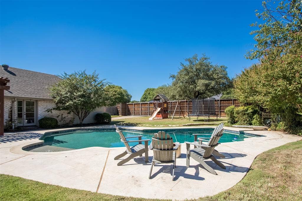 Backyard featuring an in-ground swimming pool with concrete decking, a privacy fence, and mature landscaping