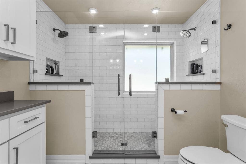 Primary bath.  Shower has white subway tiles, dual shower heads.  Quartzite countertops.