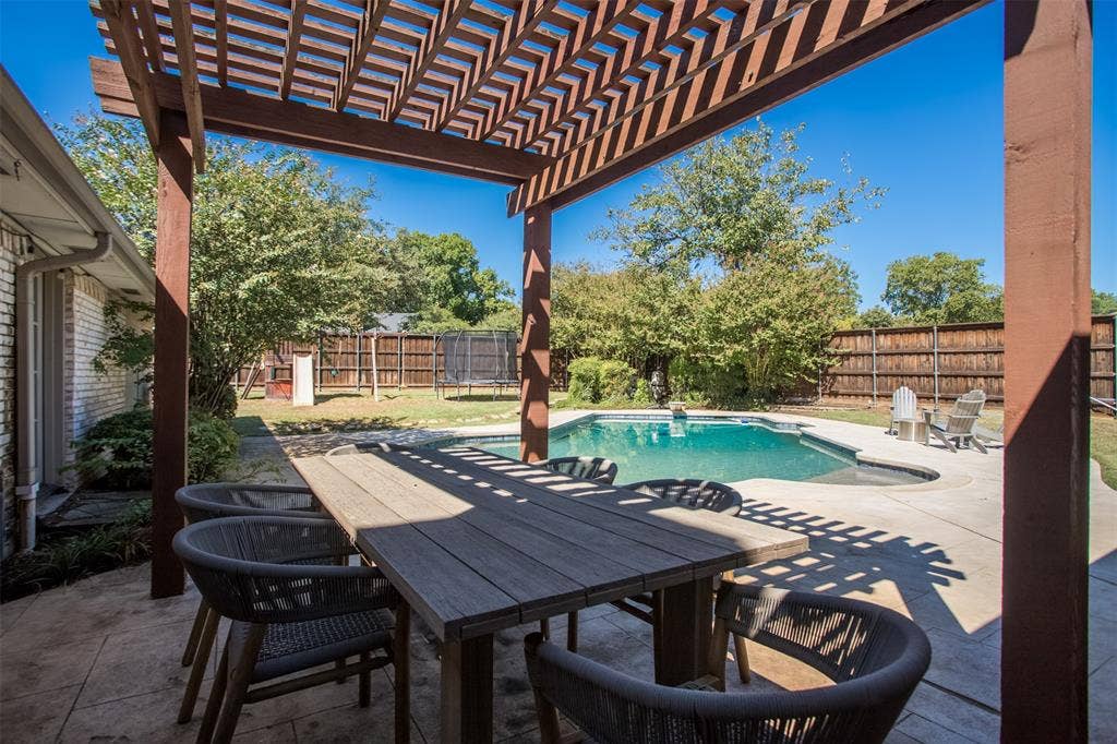 Covered patio with a wooden pergola, concrete surround, and an in-ground swimming pool.