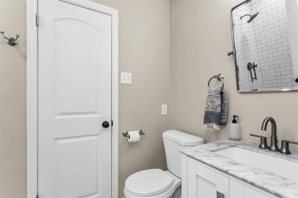 Modern bathroom featuring a white vanity, tiled shower to left.