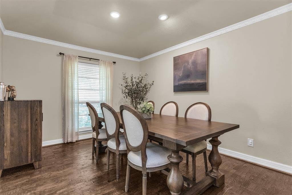 Dining room with neutral colors, recessed lighting and wood flooring.
