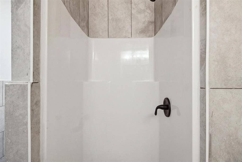 1105 Bell Drive, Greenville, TX 75401 White shower stall with a single-handle matte black faucet and light-toned tile surround