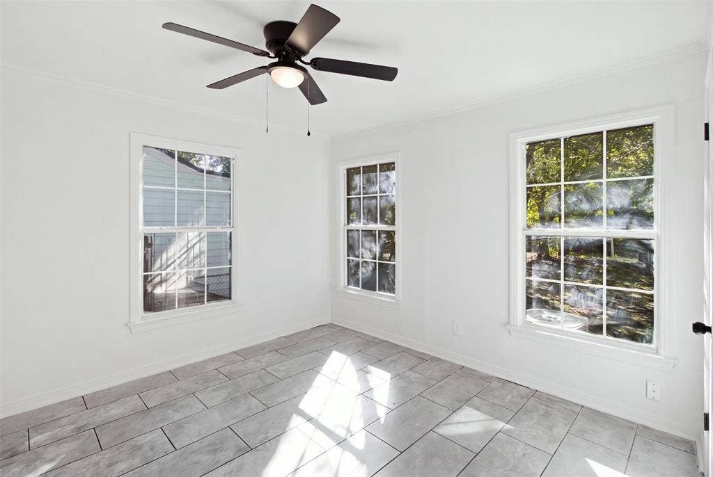 1105 Bell Drive, Greenville, TX 75401 Rectangular tile flooring, multiple double-hung windows, and a ceiling fan with integrated lighting