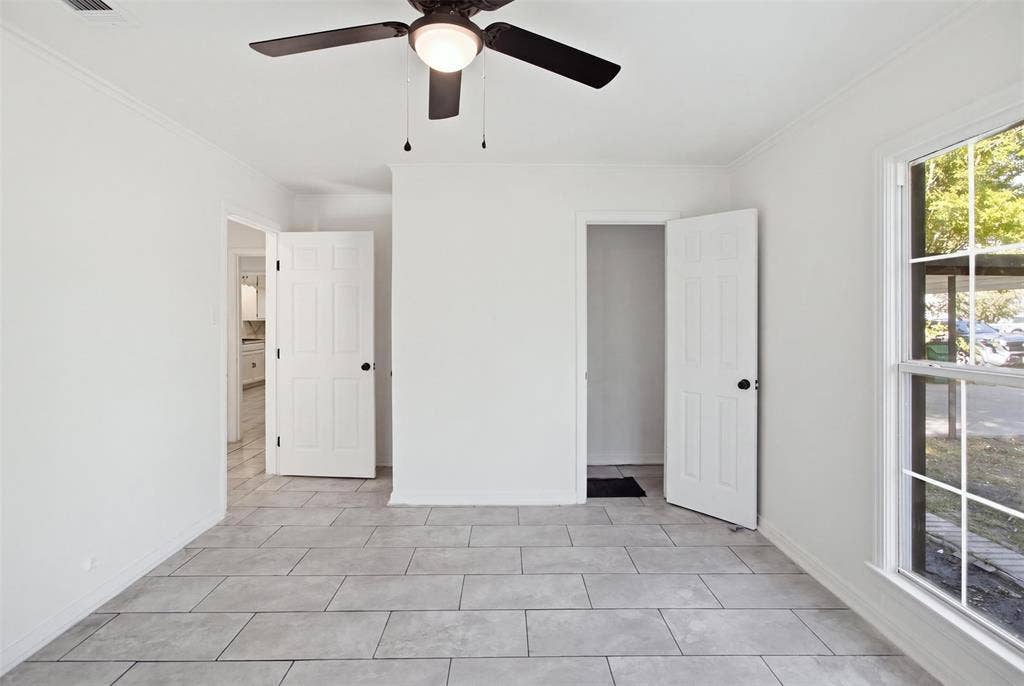1105 Bell Drive, Greenville, TX 75401 Light-toned rectangular tile flooring, white interior doors with black hardware, a ceiling fan with integrated lighting, and a multi-pane window