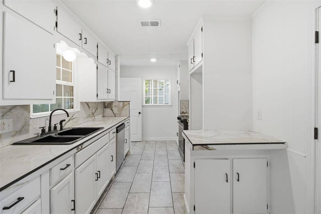 1105 Bell Drive, Greenville, TX 75401 White cabinetry with black hardware, complementing black sink basins and faucet