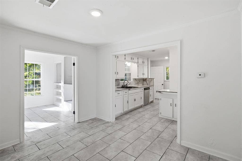 1105 Bell Drive, Greenville, TX 75401 White kitchen cabinetry, stainless steel dishwasher, and tiled flooring