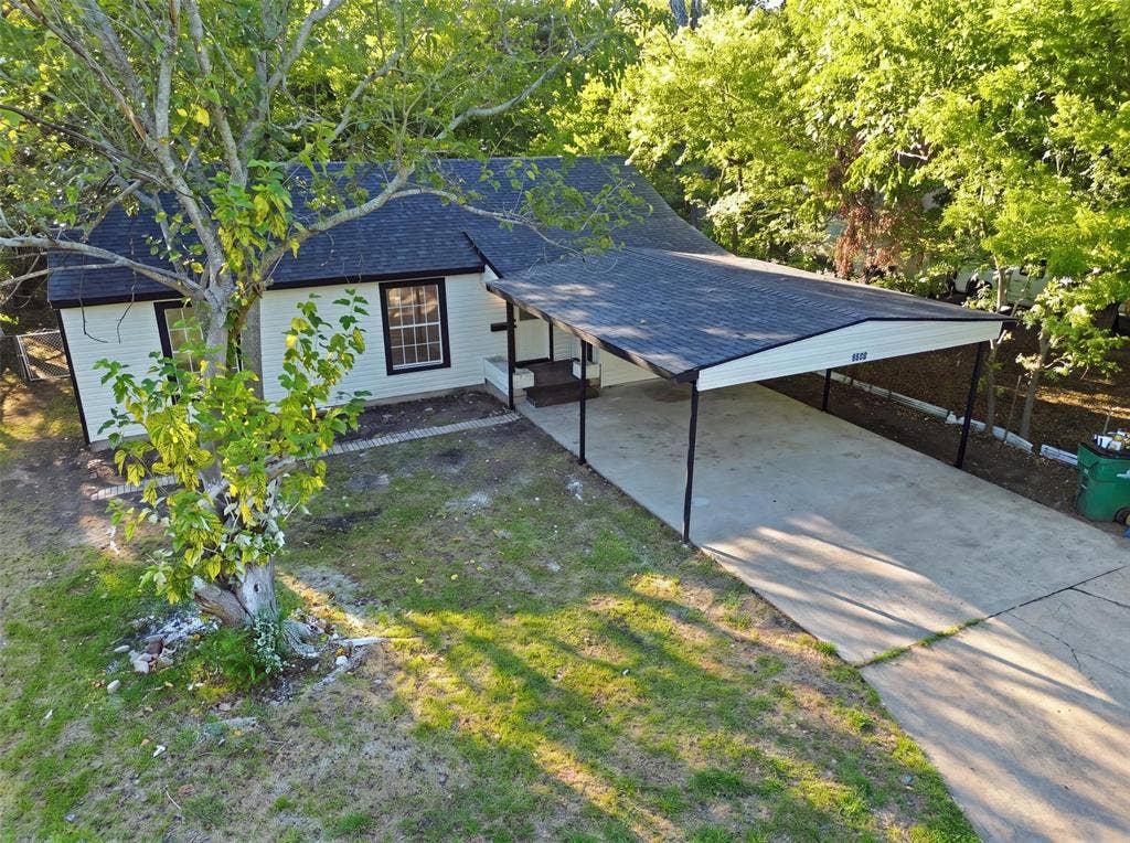 1105 Bell Drive, Greenville, TX 75401 Exterior featuring white siding, dark trim, a dark shingle roof, and a covered carport with a concrete driveway