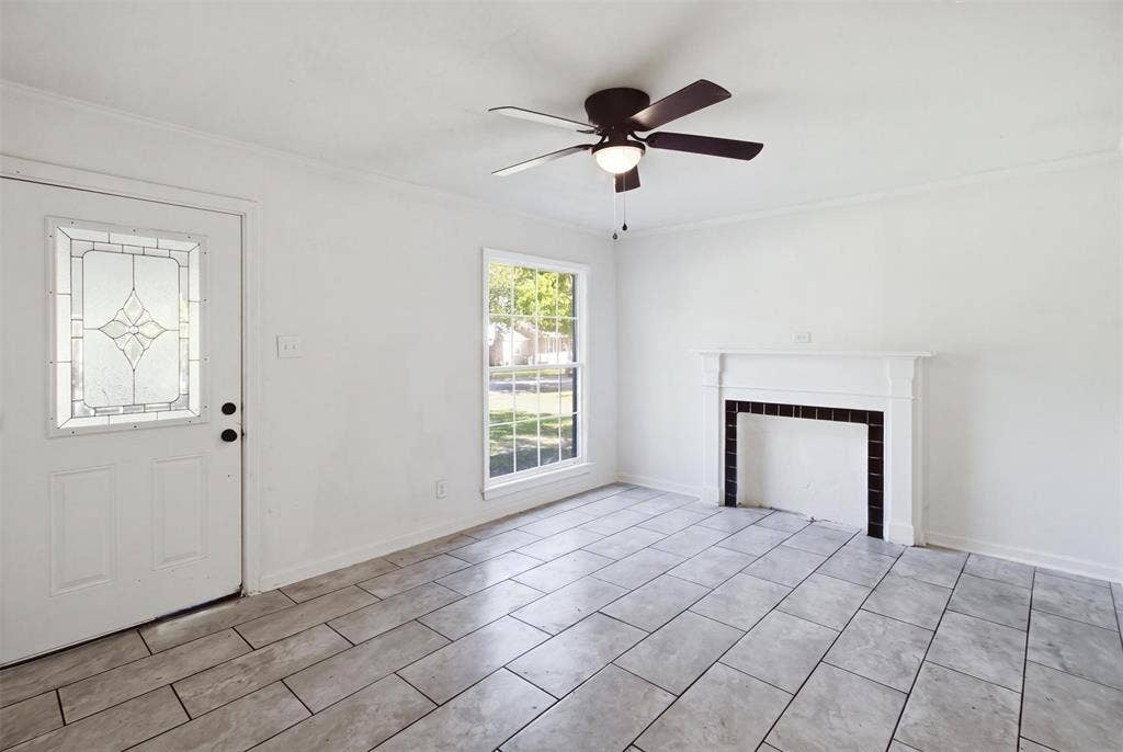 1105 Bell Drive, Greenville, TX 75401 Entry door with decorative glass insert, ceiling fan with integrated lighting, a single window, white walls, and rectangular tile flooring